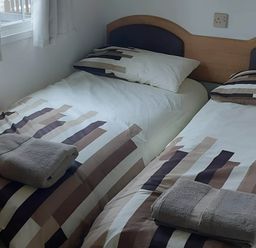 A bedroom with two beds and towels at Llanarmon-yn-Ial Mold 3-Bed Caravan, Sleeps 6 in Llanarmon-Yn-Ial