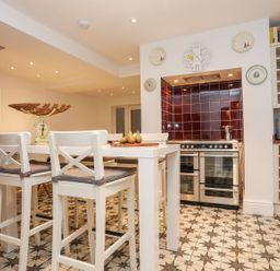 A kitchen with bar stools and kitchen appliances at Rhiwlas in Rhosneigr