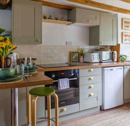 A kitchen equipped with oven, dishwasher, and table at Cotswolds Cozy Cottage Retreat - pet friendly, Finstock