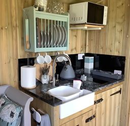 A kitchen with sink, microwave, and utensils at The Shepherds Hut at Hafoty Boeth Corwen