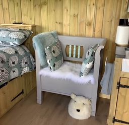 A bedroom with a bed, cushions, a bench and a sink at The Shepherds Hut at Hafoty Boeth, Corwen