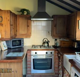 A kitchen with cabinets, stove, microwave, and sink at Quiet cottage on the rural edge of Brixham