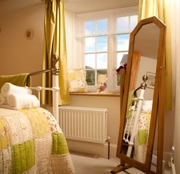 A bedroom with a bed, towels, mirror and window at Quiet cottage on the rural edge of Brixham