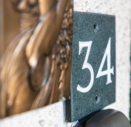 A door number 34 plaque on a wall outside a residential property in Bowness-On-Windermere