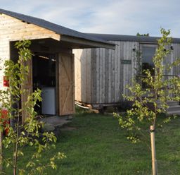Two wooden structures with doors in a grassy area at Restored circus wagon Saltburn-By-The-Sea