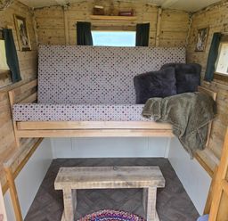 A seating area with a bench and cushions in a restored circus wagon Saltburn-By-The-Sea