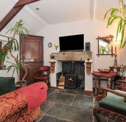 A living room with a fireplace and a television at Coach House in Camelford