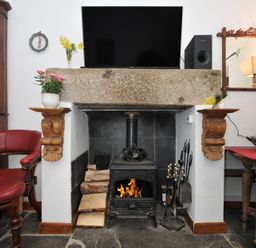 A living room with a fireplace and television at Coach House in Camelford