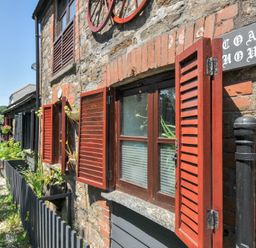 An outdoor view of the Coach House with windows and flowers at Coach House in Camelford