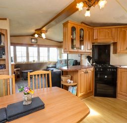 A kitchen with wooden cabinets and a table at Caravan at Argraig Llanrhyddlad near Cemaes Bay