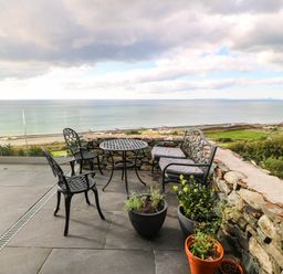 An outdoor seating area with chairs and a table overlooking the sea at Briar Bank in Barmouth