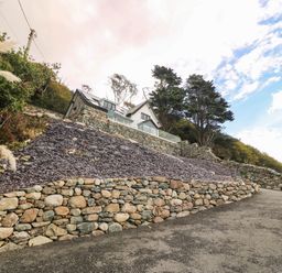 A house with a stone wall and driveway at Briar Bank in Barmouth