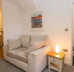 A living room with a sofa and lamp at Bobtail Cottage in Kendal