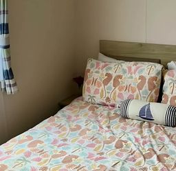 A bedroom with a bed and window at Static Caravan Hoburne Devon Bay in Paignton