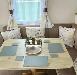A dining area with a table and cushions at Static Caravan Hoburne Devon Bay, Paignton