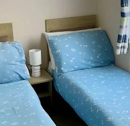 A bedroom with two beds and a bedside lamp at Static Caravan Hoburne Devon Bay in Paignton