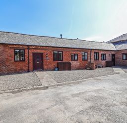 An outdoor area with a brick building and gravel pathway at Elwy Cottage in St Asaph