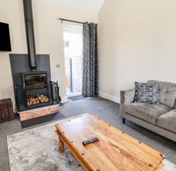 A living room with a fireplace and sofa at Elwy Cottage in St Asaph