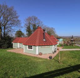 A cottage with a red roof in a grassy area at Antlers Lodge in Biddulph Moor