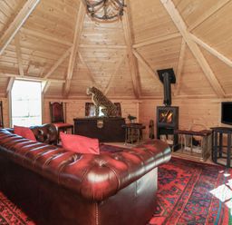 A snug with a sofa, fireplace, and television at Antlers Lodge, Biddulph Moor