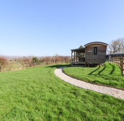 A wooden cabin with a gravel path in a grassy area at Golden Fleece in Biddulph Moor