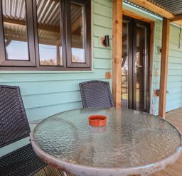 An outdoor seating area with a glass table and chairs at Golden Fleece in Biddulph Moor