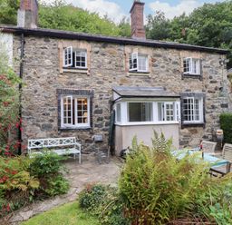 A stone house with a garden table and chairs at 3 Tre Felin in Llandygai near Bangor