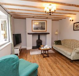 A living room with a sofa, armchair, and television at 3 Tre Felin in Llandygai near Bangor