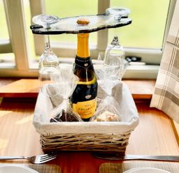 A basket with a wine bottle, glasses and snacks at Cwt Tyddyn Shepherd's Hut in Corwen