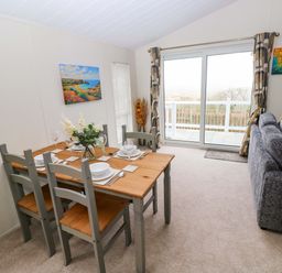 A dining area with a table and chairs at Wernlas Lodge Oxwich
