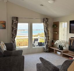 A living room with a sofa and television at Wernlas Lodge in Oxwich