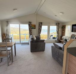 A living room with a sofa and dining table at Wernlas Lodge in Oxwich