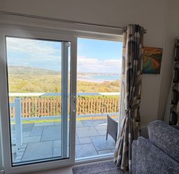 A living room with a window overlooking the landscape at Wernlas Lodge in Oxwich
