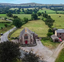 A countryside view with buildings and vehicles at Kaber Chapel near Kirkby Stephen