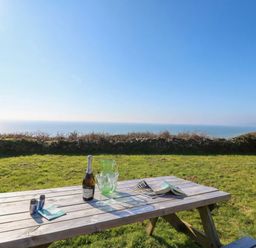 A table with drinks and a magazine overlooking the sea at The Cabin