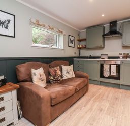 A living room with a sofa and kitchen in Robins Nest Lodge South Molton