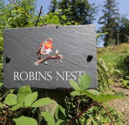 A sign with a bird illustration and text at Robins Nest Lodge South Molton