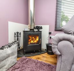 A living room with a stove and fire at Hedgehogs Lodge South Molton
