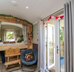 A bedroom with a bed and chair at Valley View Shepherd's Hut South Molton