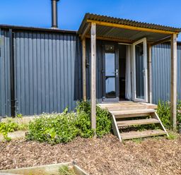 A hut with steps and flower beds at Hares Hideaway Shepherd's Hut South Molton