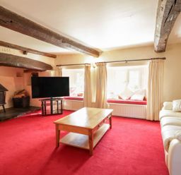 A living room with a fireplace and television at The Farmhouse in Keswick