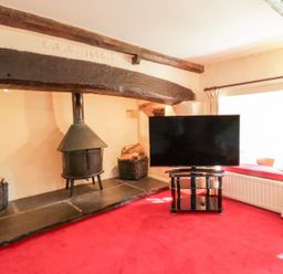 A living room with a fireplace and television at The Farmhouse in Keswick