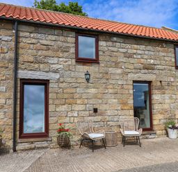 An outdoor area with stone walls and chairs at Swallow Cottage Lealholm
