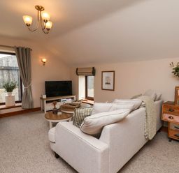 A living room with a sofa and television at Swallow Cottage in Lealholm