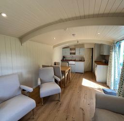A living room with chairs and a kitchen area at The Orchard in Ringstead
