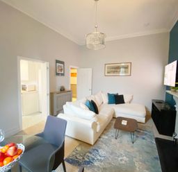 A living room with a sofa, table, and television at 2A Redcliffe in Torquay