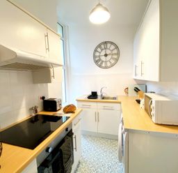 A kitchen with a clock, sink, and appliances at 2A Redcliffe in Torquay