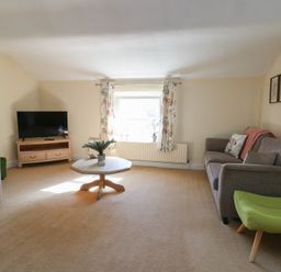 A living room with a television and sofa at Castle Gardens Apartment Beaumaris