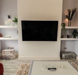 A living room with a TV and shelves at Sugar Loft Silloth
