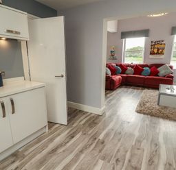 A kitchen area leading to a living room with a red sofa at Sugar Loft in Silloth